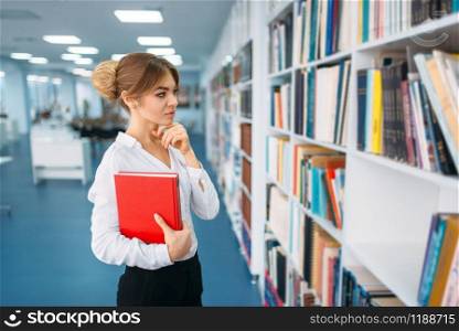 Young woman looking book at the shelf in library. Female person in reading room. Young woman looking book at the shelf in library