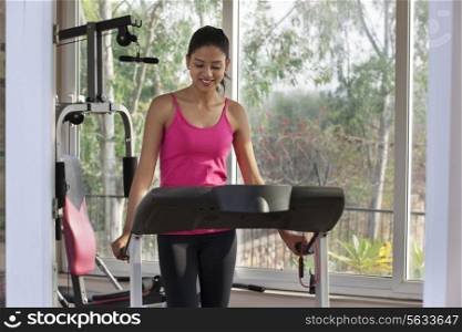 Young woman looking down while standing on treadmill