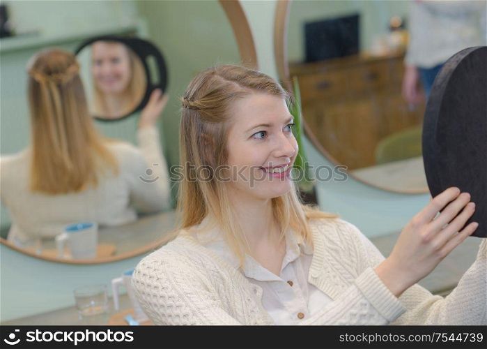 young woman looking in a mirror at the hairdresser