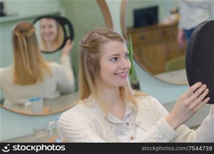 young woman looking in a mirror at the hairdresser