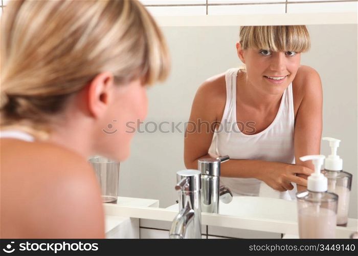 Young woman looking in the bathroom mirror