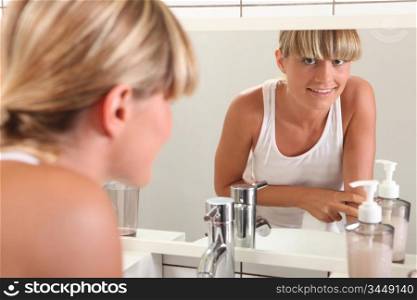 Young woman looking in the bathroom mirror