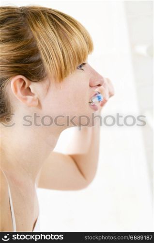 Young woman looking into a mirror brushing her teeth