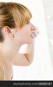 Young woman looking into a mirror brushing her teeth