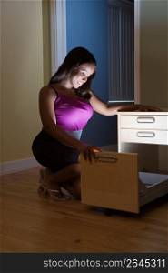 Young woman looking into illuminated filing cabinet