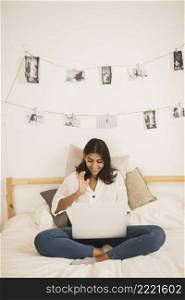 young woman looking laptop bed
