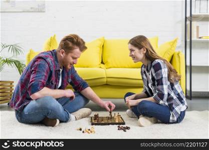 young woman looking man playing chess game living room