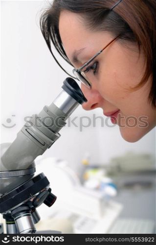 young woman looking on microscope