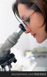 young woman looking on microscope
