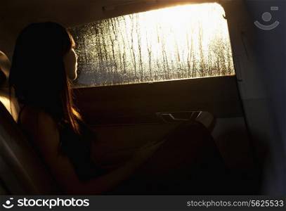 Young woman looking out the window of the car and contemplating on a rainy night in Beijing