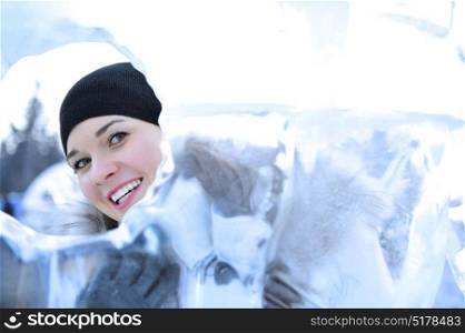 Young woman looking through a hole in the ice during winter time