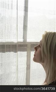Young woman looking through window, close-up