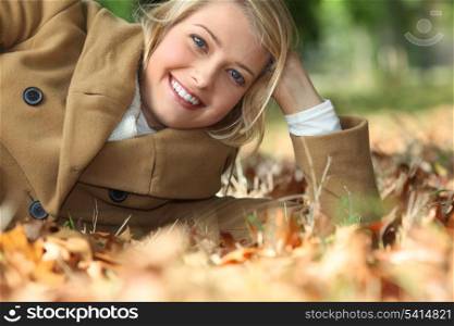 Young woman lying amidst autumnal foliage in the woods