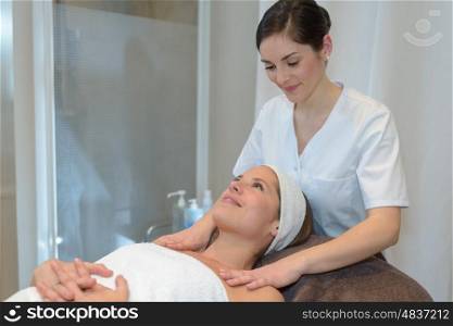 young woman lying and having face massage in spa