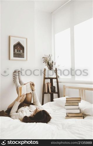 young woman lying bed with book