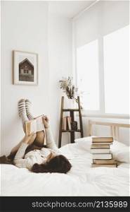 young woman lying bed with book