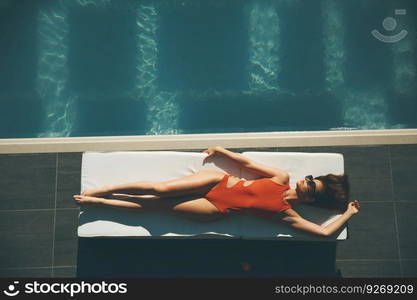 Young woman lying by swimming pool  at hot summer day