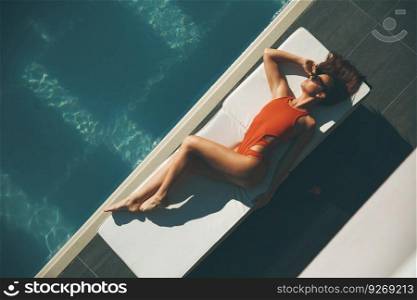 Young woman lying by swimming pool  at hot summer day