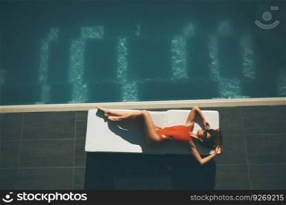Young woman lying by swimming pool  at hot summer day