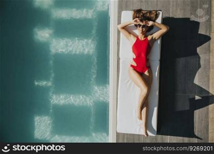 Young woman lying by the pool on bed