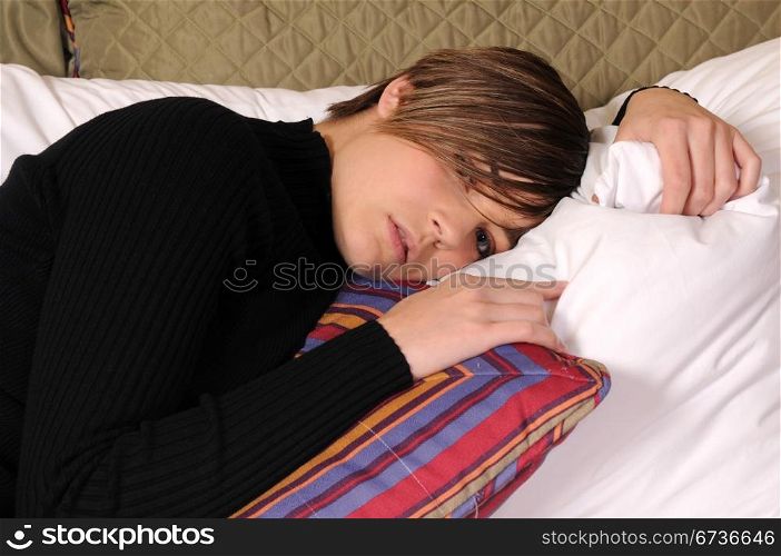 Young woman lying in a hotel bed surrounded by pillows