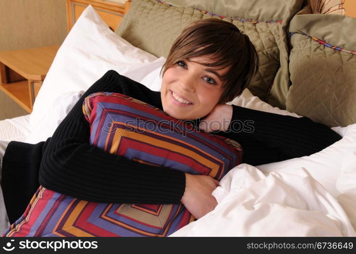 Young woman lying in a hotel bed surrounded by pillows