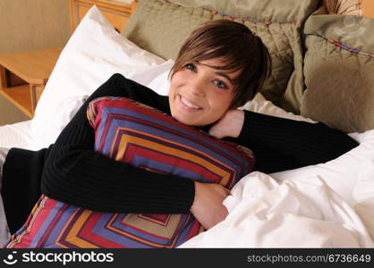 Young woman lying in a hotel bed surrounded by pillows