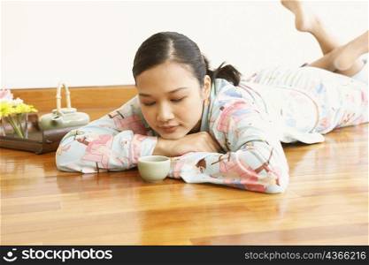 Young woman lying in front of a tea cup