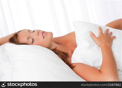 Young woman lying in white bed and sleeping