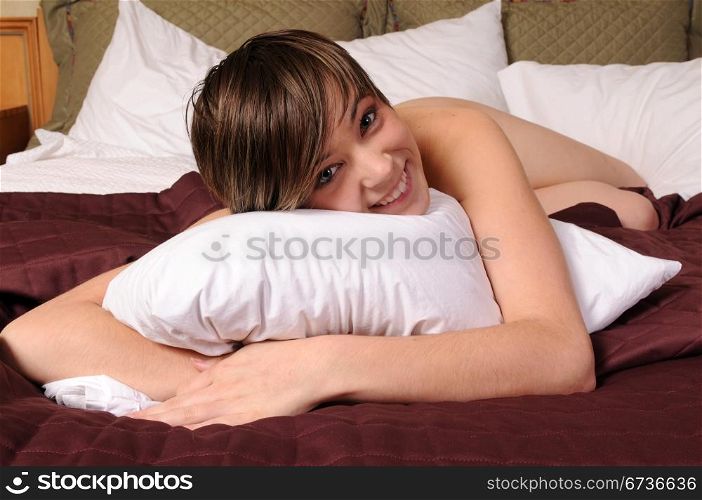 Young woman lying nude in bed