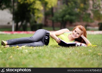 Young woman lying on a carpet of leaves in autumn park