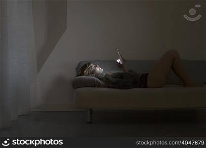 Young woman lying on bed using digital tablet