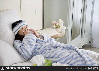 Young woman lying on bed with common cold