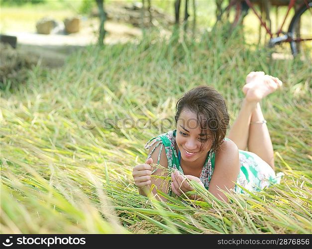 Young woman lying on meadow playing with grass smiling