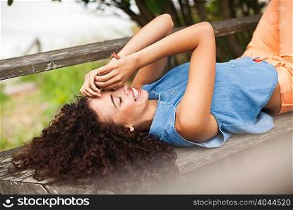 Young woman lying on picnic table, smiling