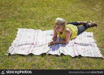 Young woman lying on rug on park grass