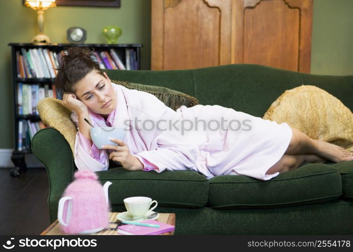 Young woman lying on sofa at home eating a sweet treat