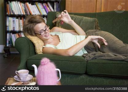 Young woman lying on sofa at home eating chocolate