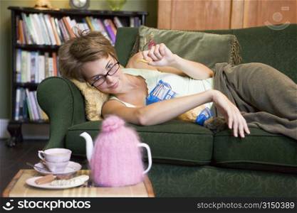 Young woman lying on sofa at home eating potato chips