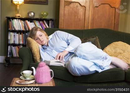 Young woman lying on sofa at home waiting by telephone