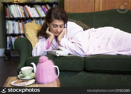 Young woman lying on sofa at home watching telephone
