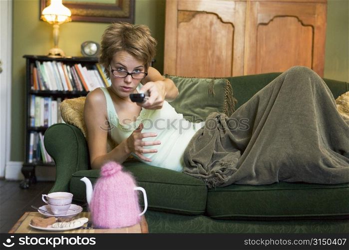 Young woman lying on sofa at home watching television