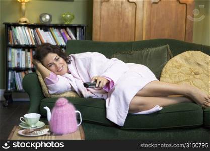 Young woman lying on sofa at home watching television