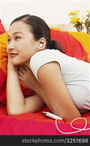 Young woman lying on the bed and listening to music on headphones
