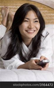 Young woman lying on the bed and watching television