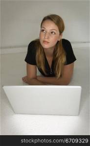 Young woman lying on the floor in front of a laptop