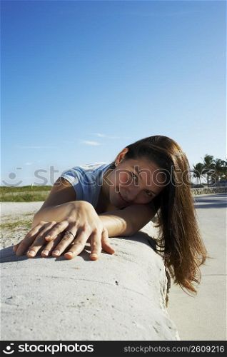 Young woman lying on wall at beach