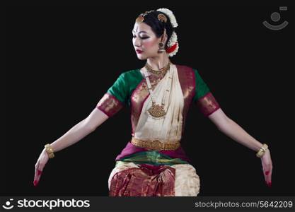 Young woman making Bharatanatyam gesture called Dola-Hastam on black background