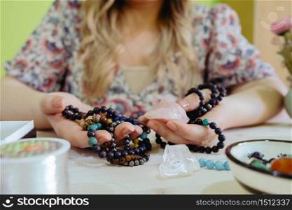 Young woman making crystal jewelery necklace and bracelet at home manually