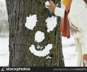 Young woman making face for tree using snow